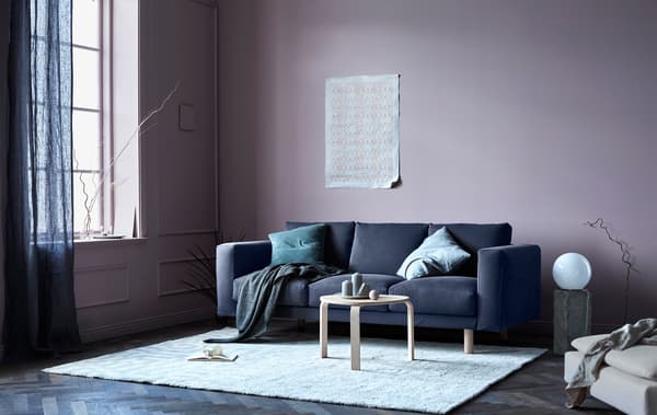 Canapé gris avec coussins et plaids dans un séjour aux accents naturels.