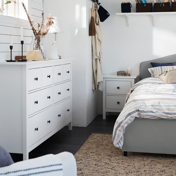 Cassettiera HEMNES con 8 cassetti sotto a una finestra, accanto al letto HAUGA in una camera da letto in stile tradizionale - IKEA