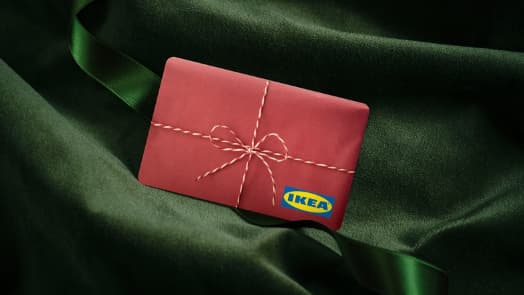 Červená dárková karta IKEA s grafikou mašličky a logem IKEA na zeleném sametu.