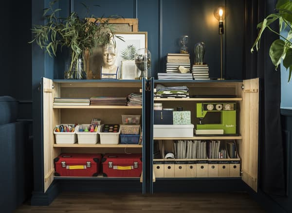 Ces deux armoires IVAR contiennent des magazines bien rangés, une machine à coudre et d’autres objets.