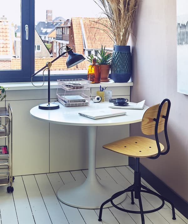 Chaise pivotante et table ronde avec lampe de bureau.