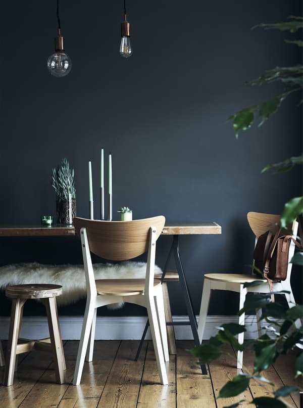 Chaises et table sur fond de mur bleu foncé.