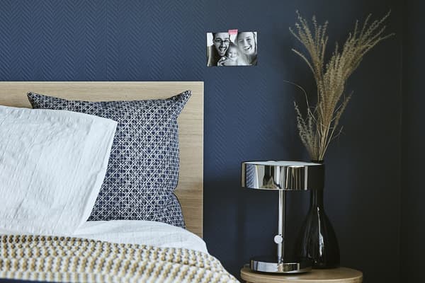 Chambre à coucher bleu foncé avec lit et tabouret en guise de table de chevet.