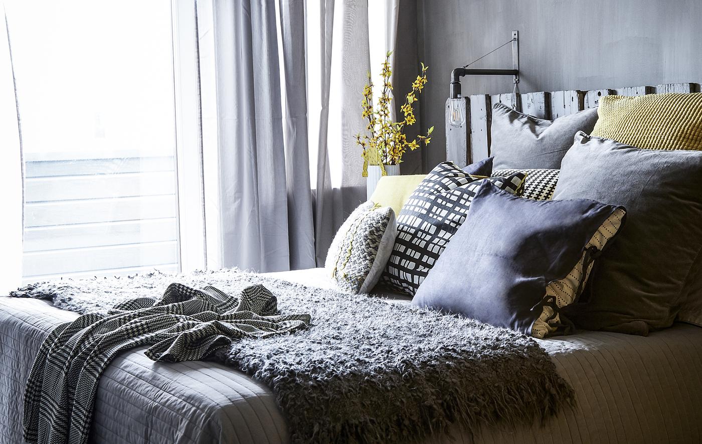Chambre avec déco grise et coussins jaunes.