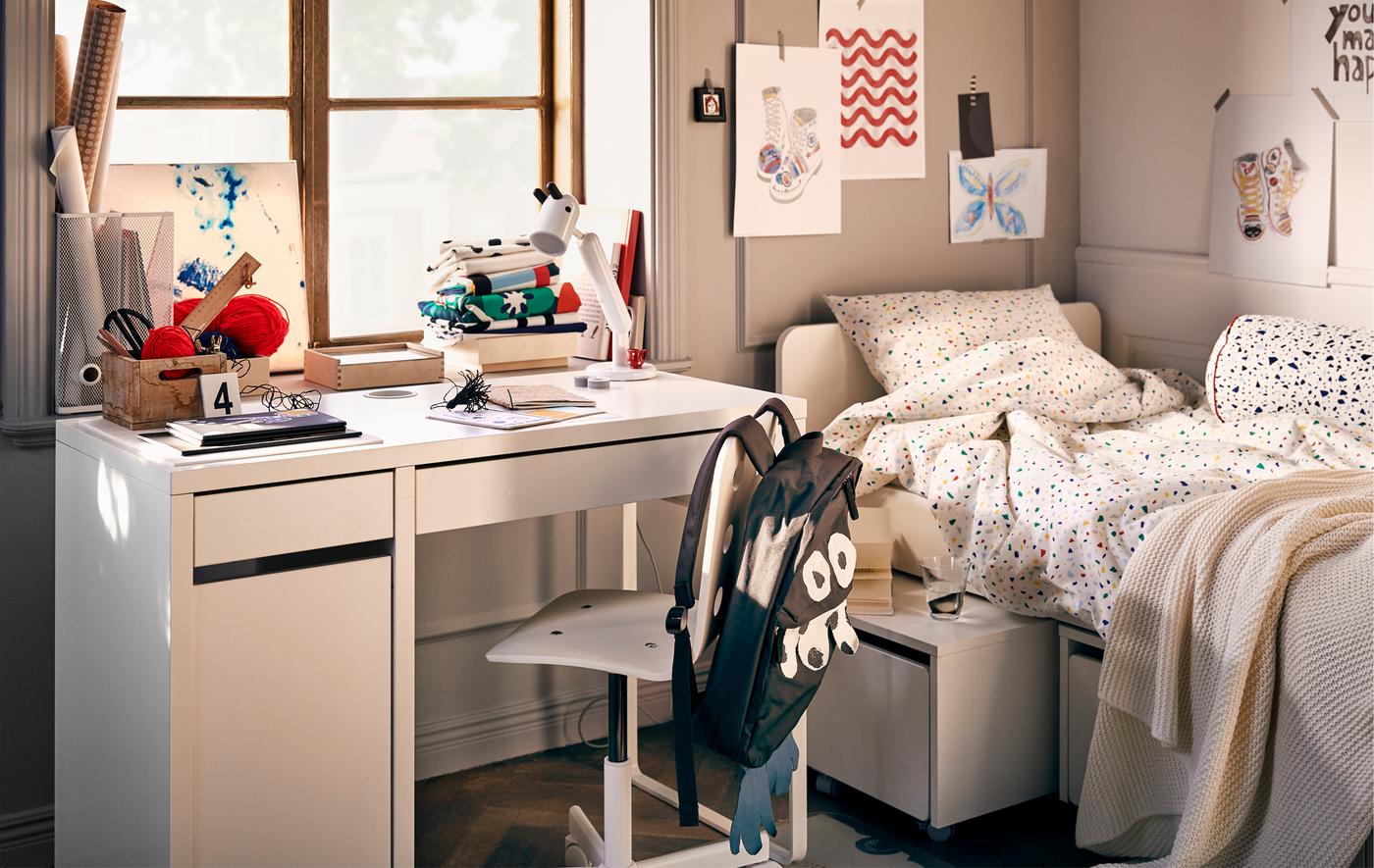 Chambre d'enfant avec lit, dessins sur les murs et espace de travail comprenant bureau MICKE, chaise pivotante et lampe KRUX.