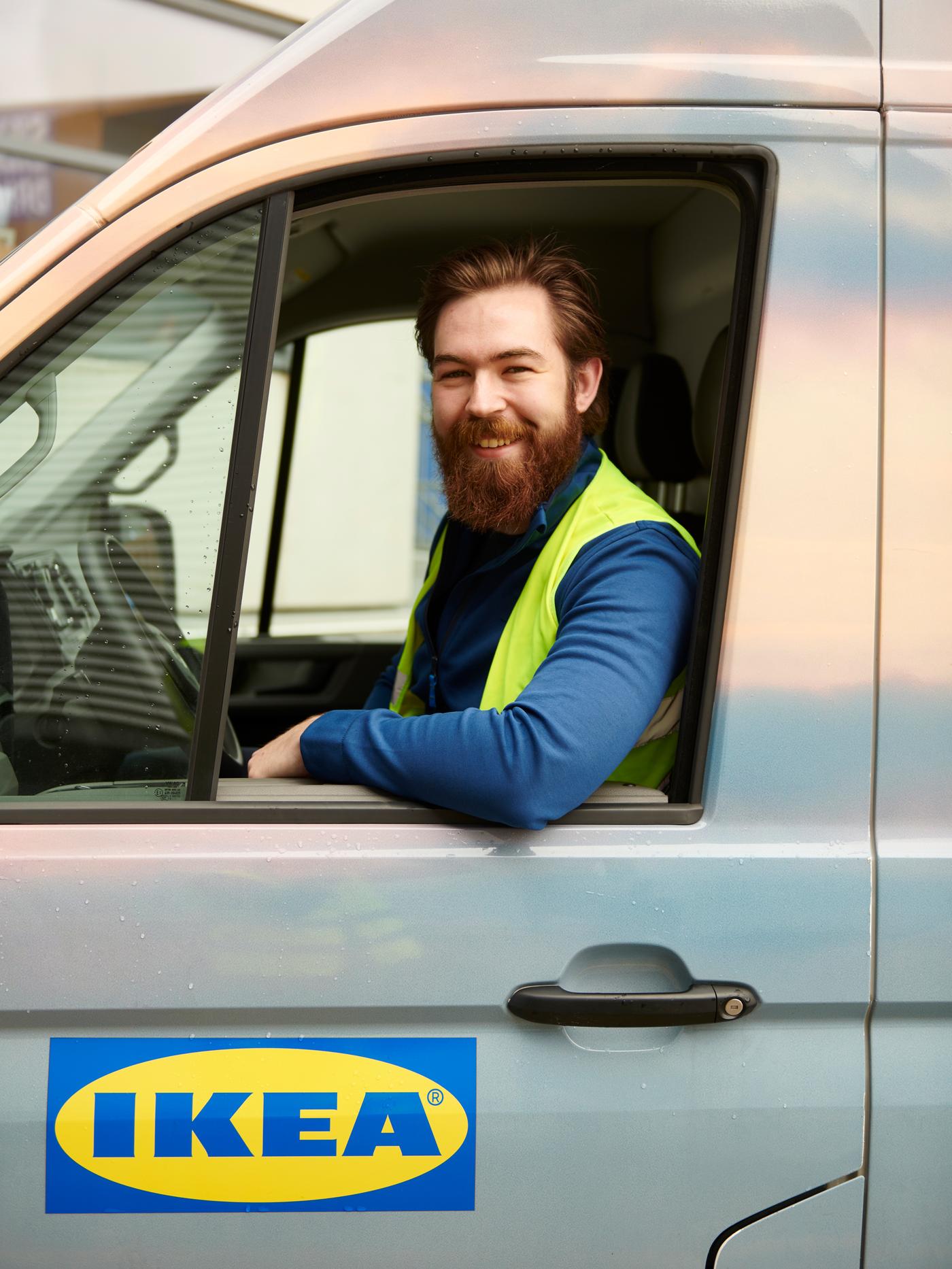 Chauffeur d’une camionnette IKEA derrière son volant, vitre baissée et coude à la portière. 