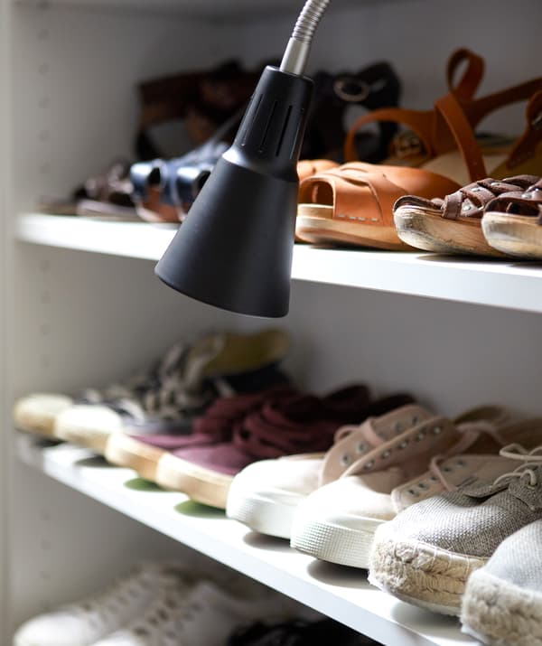 Chaussures alignées sur des étagères avec une lampe de travail noire.
