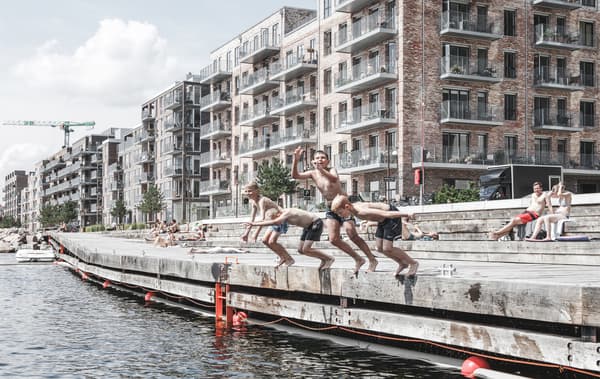 Children jumping into the river with large apartment blocks behind.