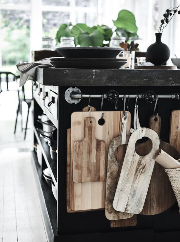 Chopping boards hanging on a rail in a black kitchen.