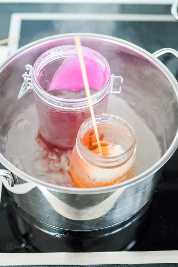 Cire colorée dans des récipients en verre chauffés à l'eau chaude