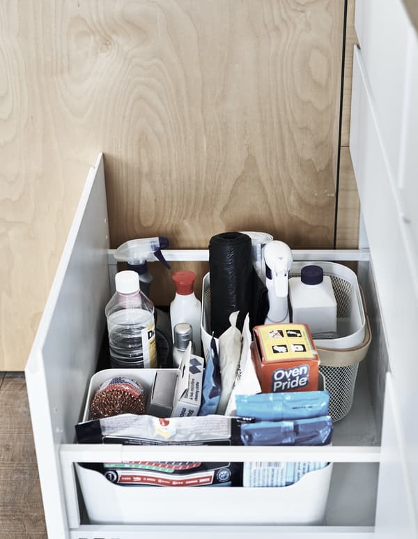 Cleaning products stored in boxes inside a drawer.