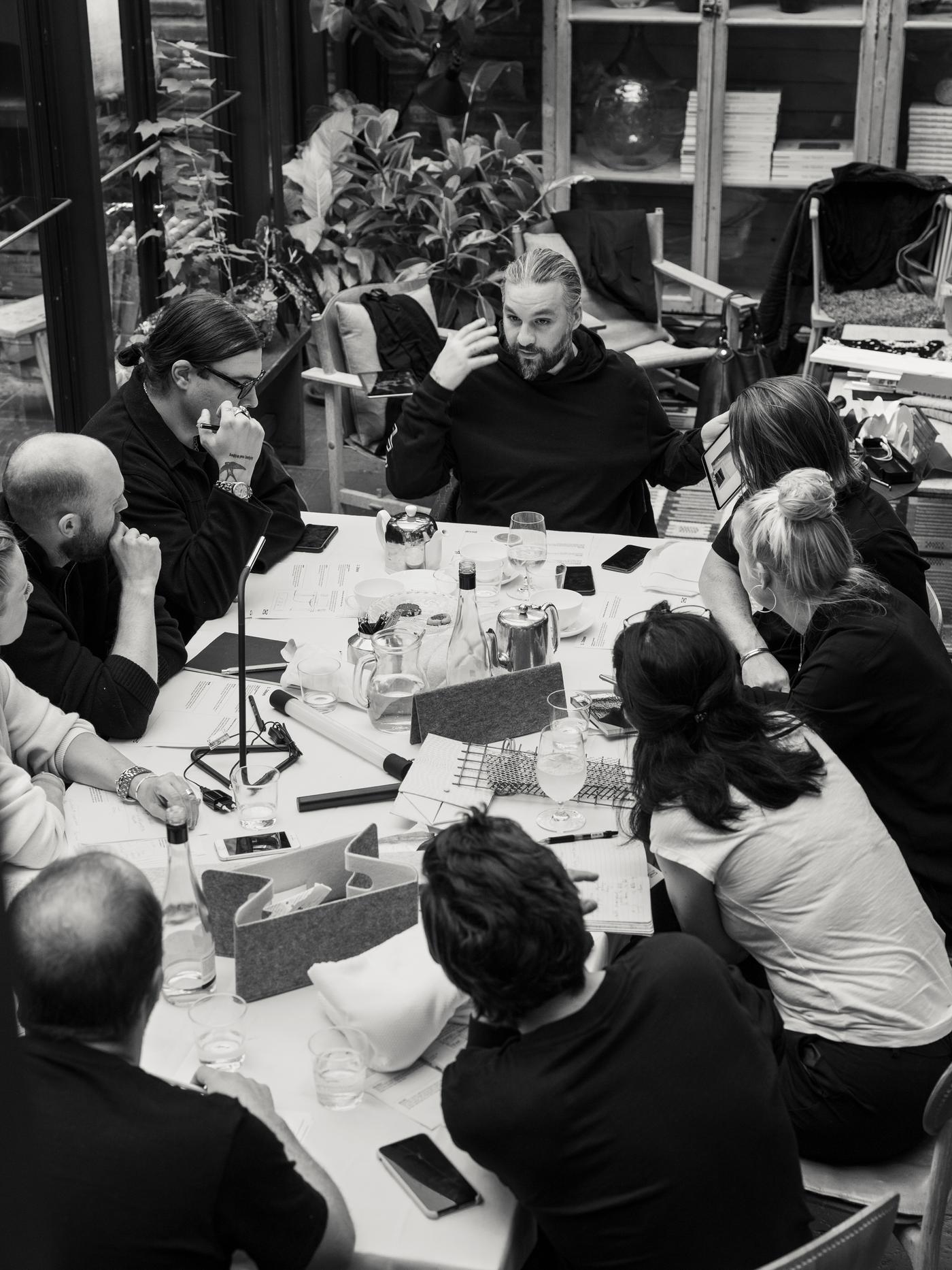 Členové Swedish House Mafia a návrháři IKEA sedí u stolu plného materiálů, papírů, sklenic a pokojových rostlin.