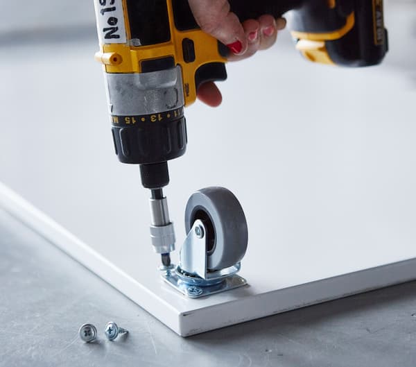 Close-up of a castor being attached to a board.