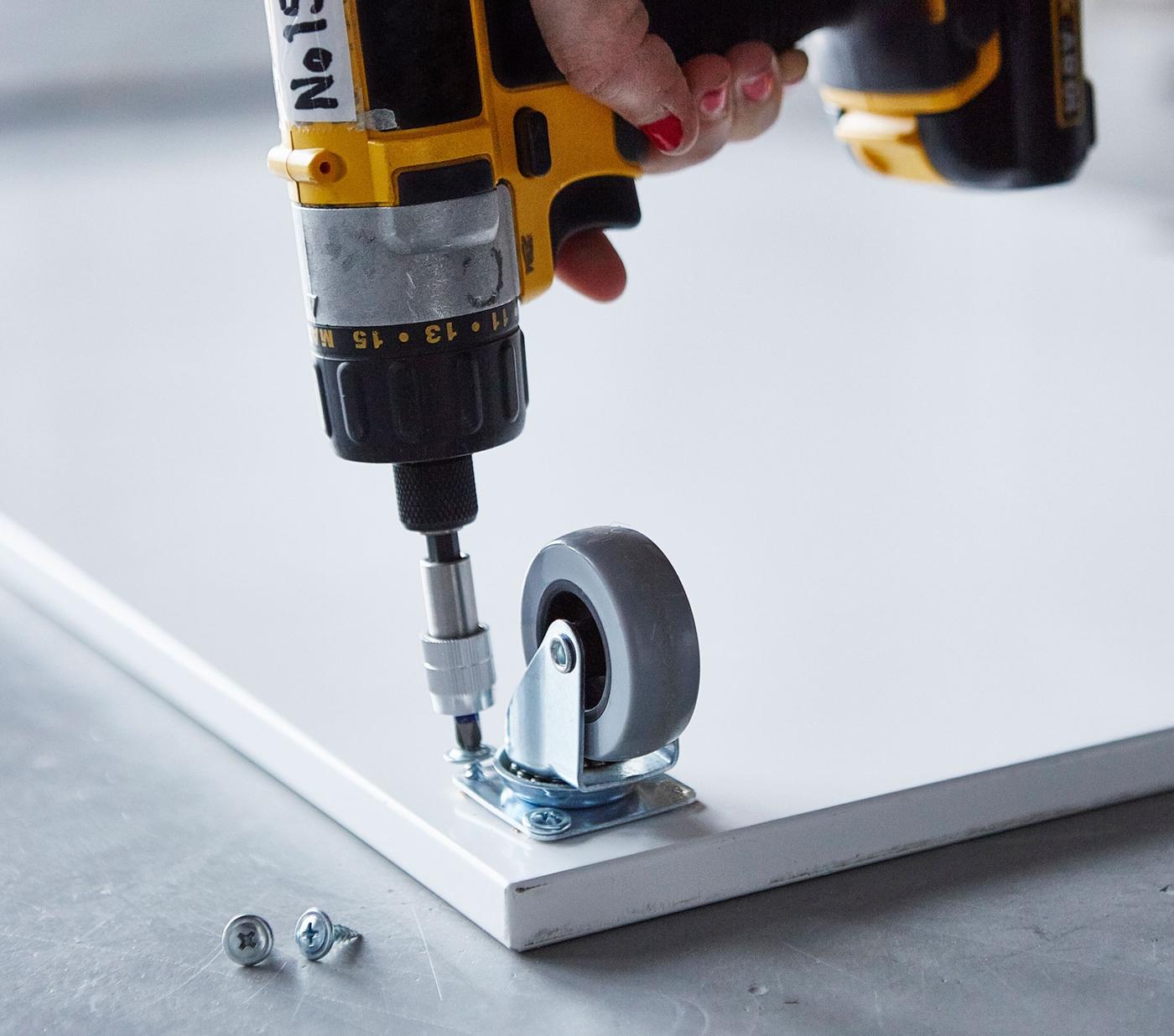 Close-up of a castor being attached to a board.