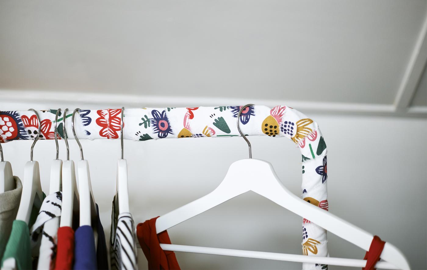 Close-up of a clothes rail wrapped in fabric with clothes on hangers.
