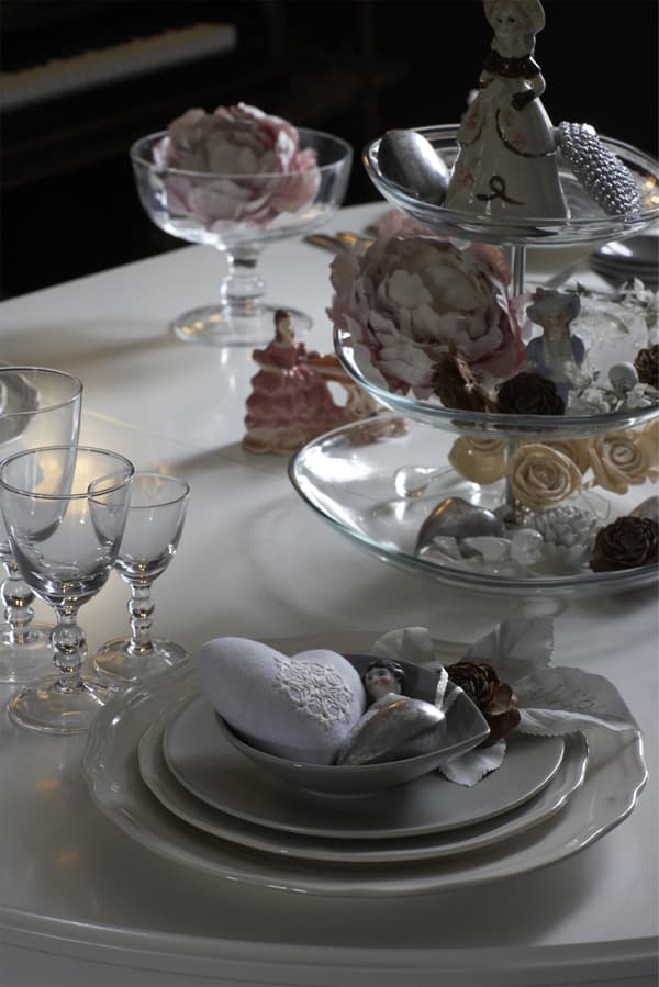 Close-up of a dinner table set with glasses and floral decorations.