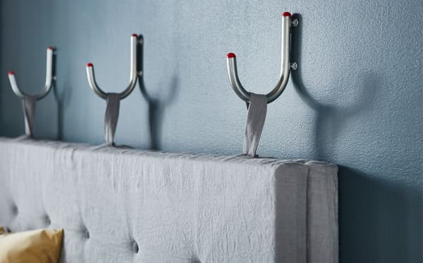 Close-up of a sofa backrest hanging on three wall hooks.