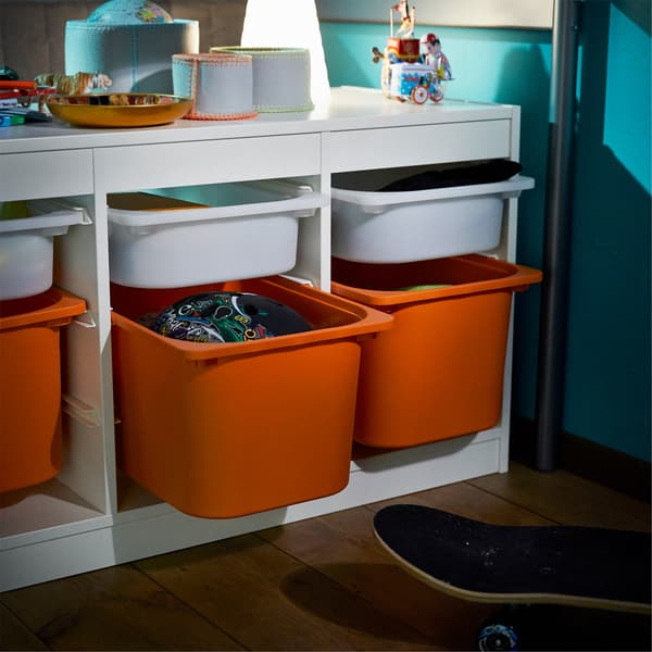 Close-up of a white storage bench with small plastic boxes in white and larger ones in orange.