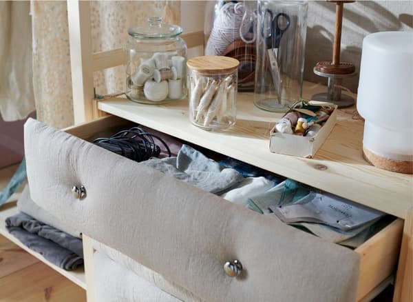 Close-up of an open chest of drawers, with fabric attached to the front.