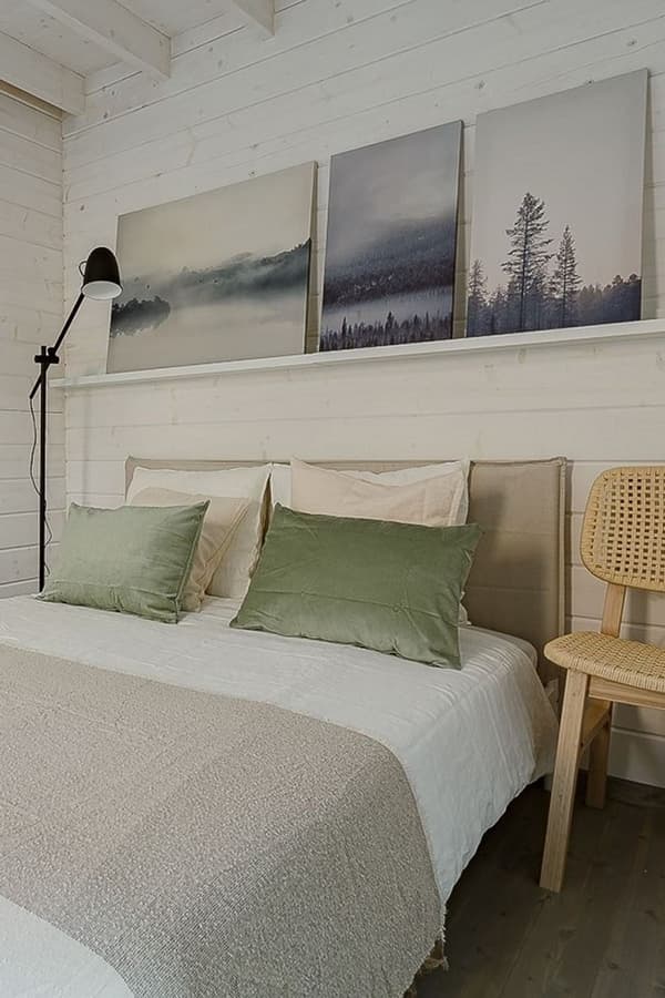 Close-up of bed with green pillows and forest-themed artwork