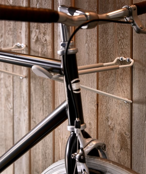 Close-up of how the bike frame rests on the rack, consisting of two slim hooks perpendicular to the wall.