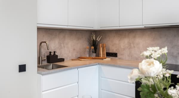 Close-up of modern kitchen countertop with sink, faucet, and wooden accessories.
