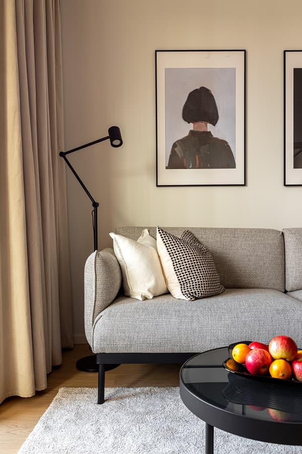 Close-up of sofa with decorative cushions, wall art, and coffee table with fruit bowl.