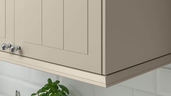 Close-up of the corner of a beige kitchen cabinet with stainless knobs.