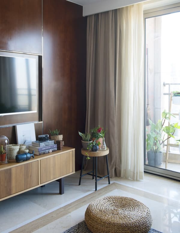 Close-up of the corner of a living room with brown sideboard and stool.