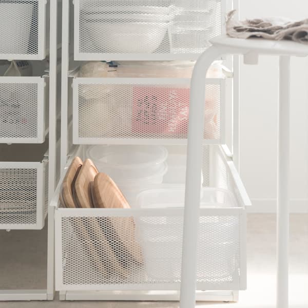 Close-up of two IKEA LENNART draw units behind a stool, filled with tableware and groceries.