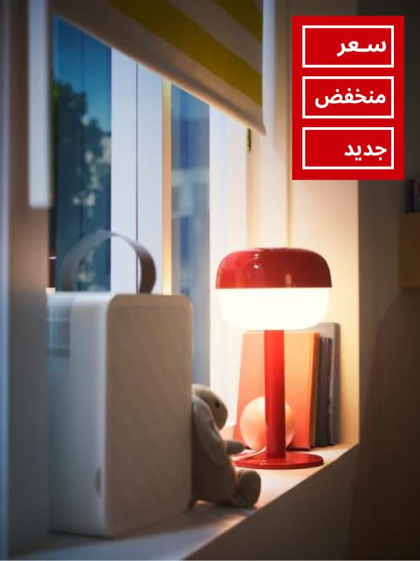 Close-up of window with a block-out roller blind, an UPPÅTVIND air-purifier and a table lamp standing on the window sill.