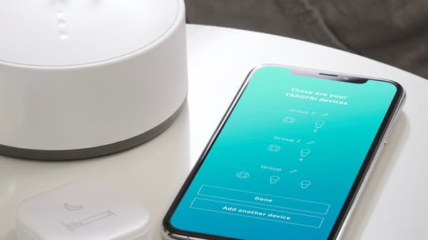Close-up view of the TRÅDFRI gateway device and the IKEA home smart app.