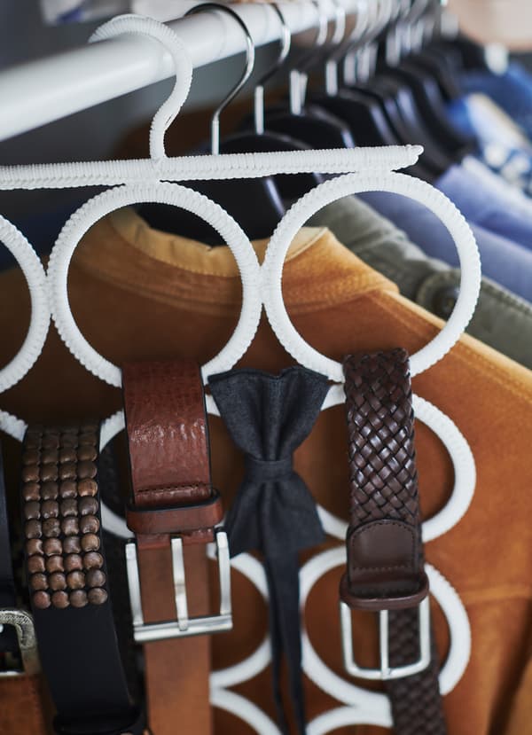 Closeup of IKEA KOMPLEMENT white hangers, which comes with many circular hoops to hold belts, bowties and ribbons.