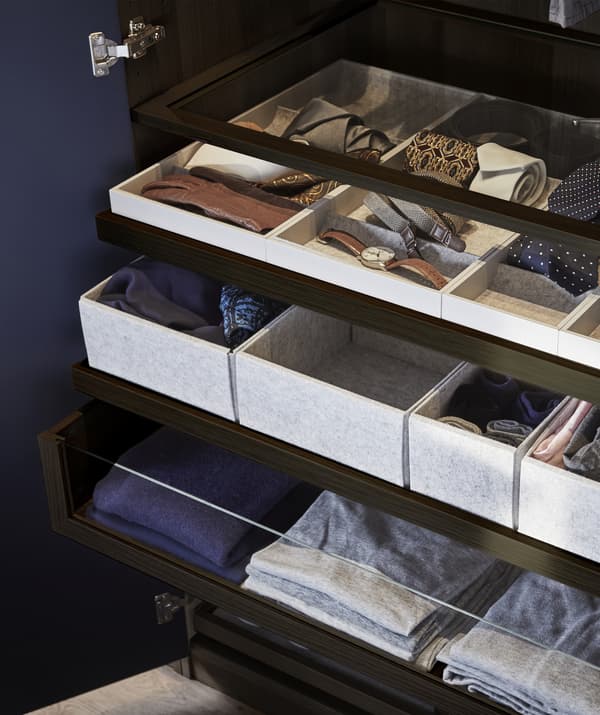 Clothes and accessories stored in drawers, trays, inserts and shelves.