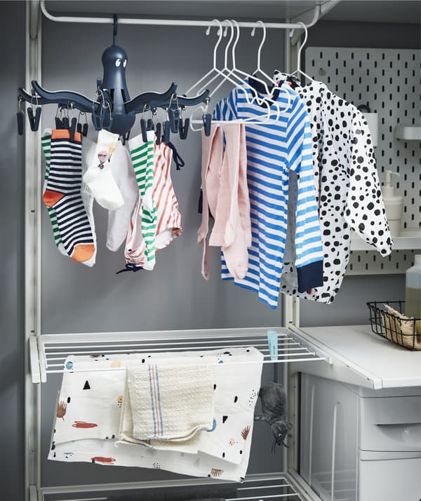 Clothes drying on hangers and pegs on tiered rails.