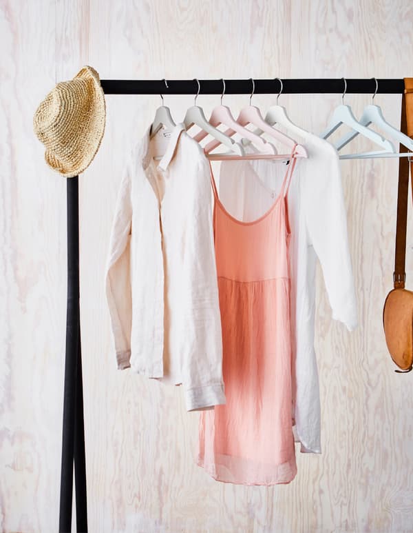 Clothes hanging on hand-painted BUMERANG hangers on a black, free-standing clothes rail.
