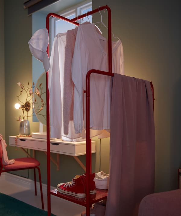 Clothes rack with garments and shoes placed perpendicular to the wall, as a room divider between recliner and make-up spot.