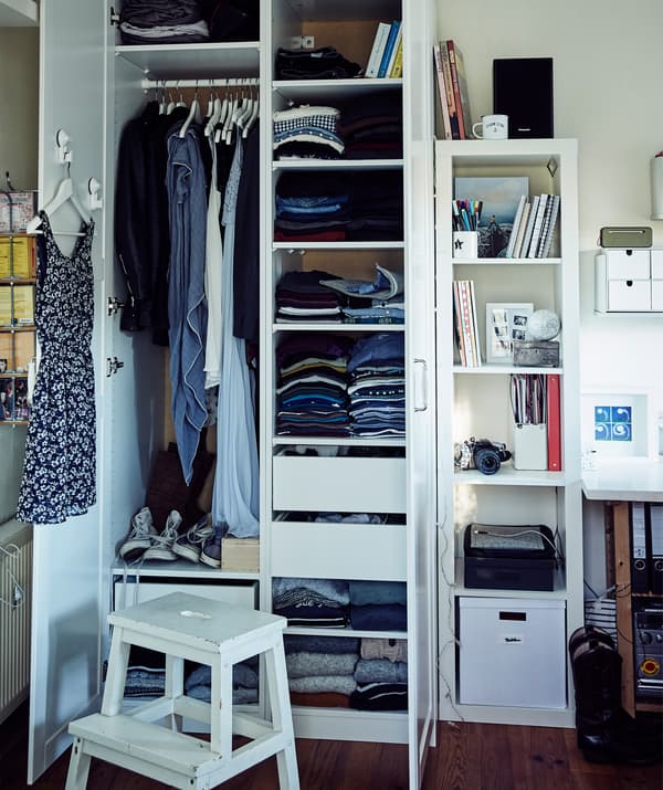 Clothes stacked on shelves and hanging from a rail inside Stine’s wardrobe.
