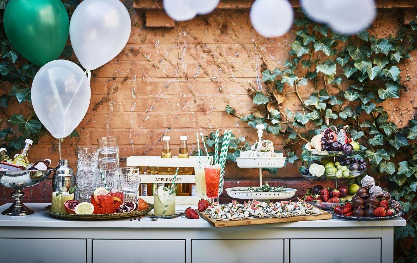 Cocktails and appetizers sit on top of a chest of drawers in a courtyard.