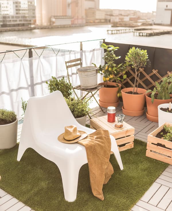 Coin détente sur le toit aménagé avec un fauteuil et un cageot en bois en guise de petite table.