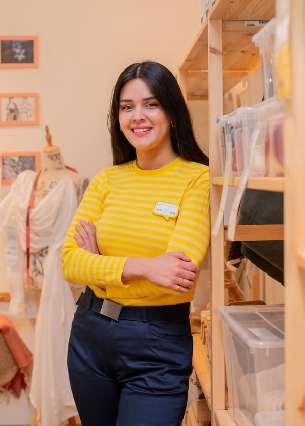 Colaboradora IKEA con su polera azul con rayas leyendo una tarjeta blanca con la palabra TACK en negro.
