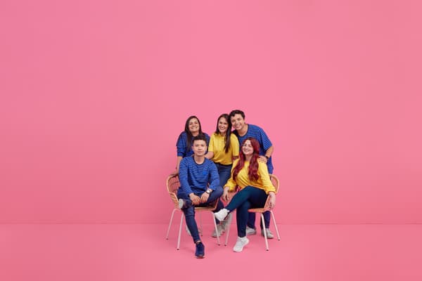 Colaboradores alegres y sentados en conjunto con un fondo fucsia