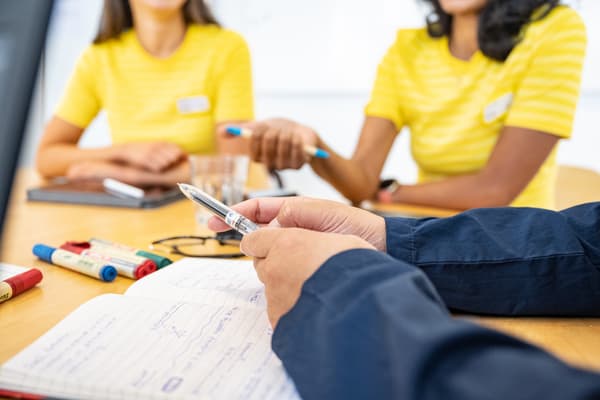 Colaboradores IKEA en una mesa de reuniones, con lápices y cuadernos.