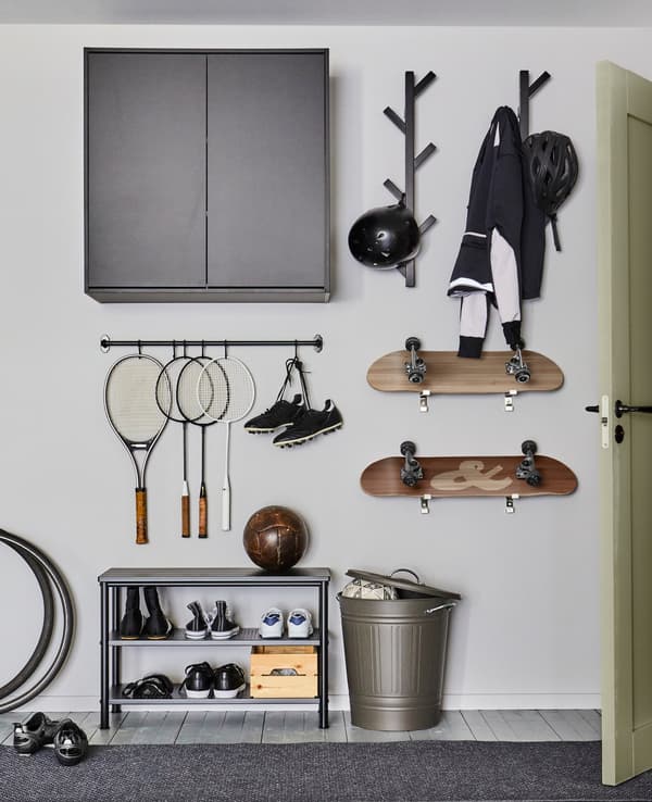 Collectie sportuitrusting en skateboards die aan de muur hangen met behulp van stangen en haken.