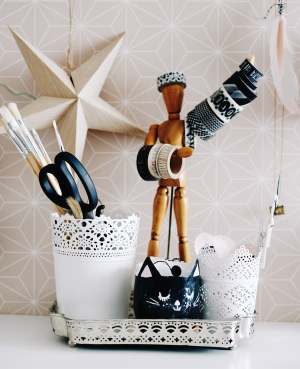 Collection de cache-pots, outils et poupée artiste, sur un bureau.