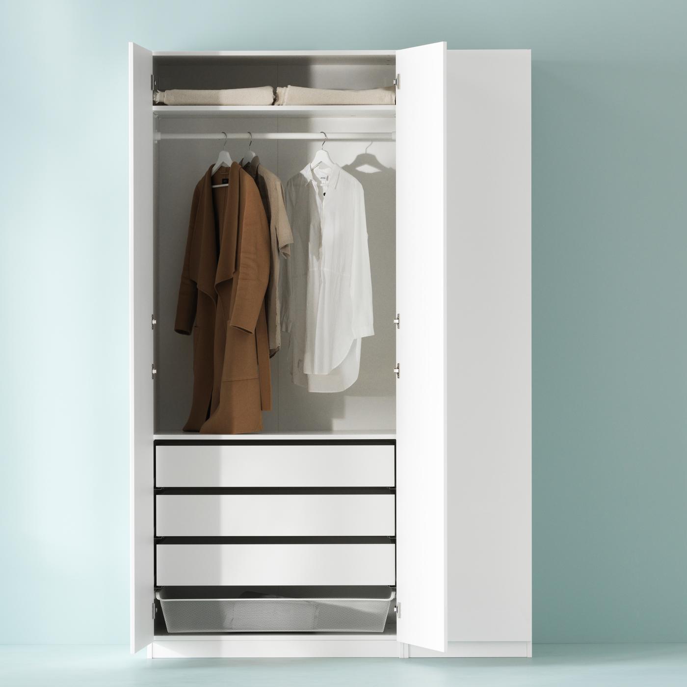 Combinaison d’armoire-penderie PAX blanche contre un mur vert pâle avec deux portes ouvertes et trois vêtements sur cintres.