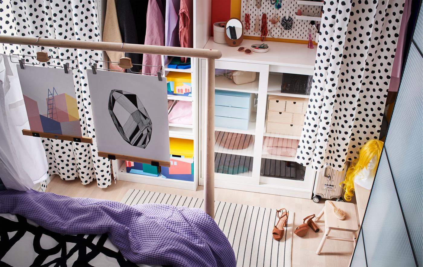 Combination of open and closed storage along a wall, a corridor forming between the curtains hung in front and a bed end.