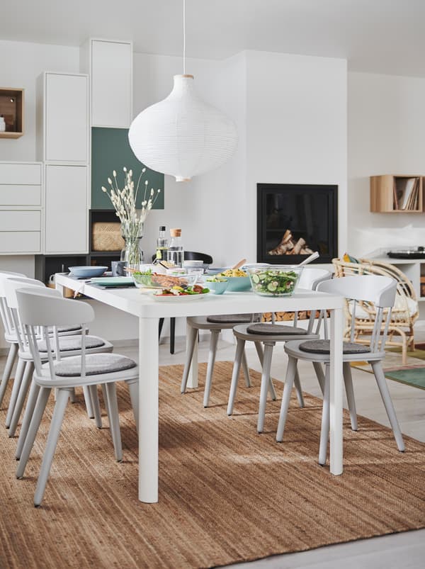 Combined living and dining room interior with fireplace, wall storage and a TINGBY dining table with OMTÄNKSAM chairs.