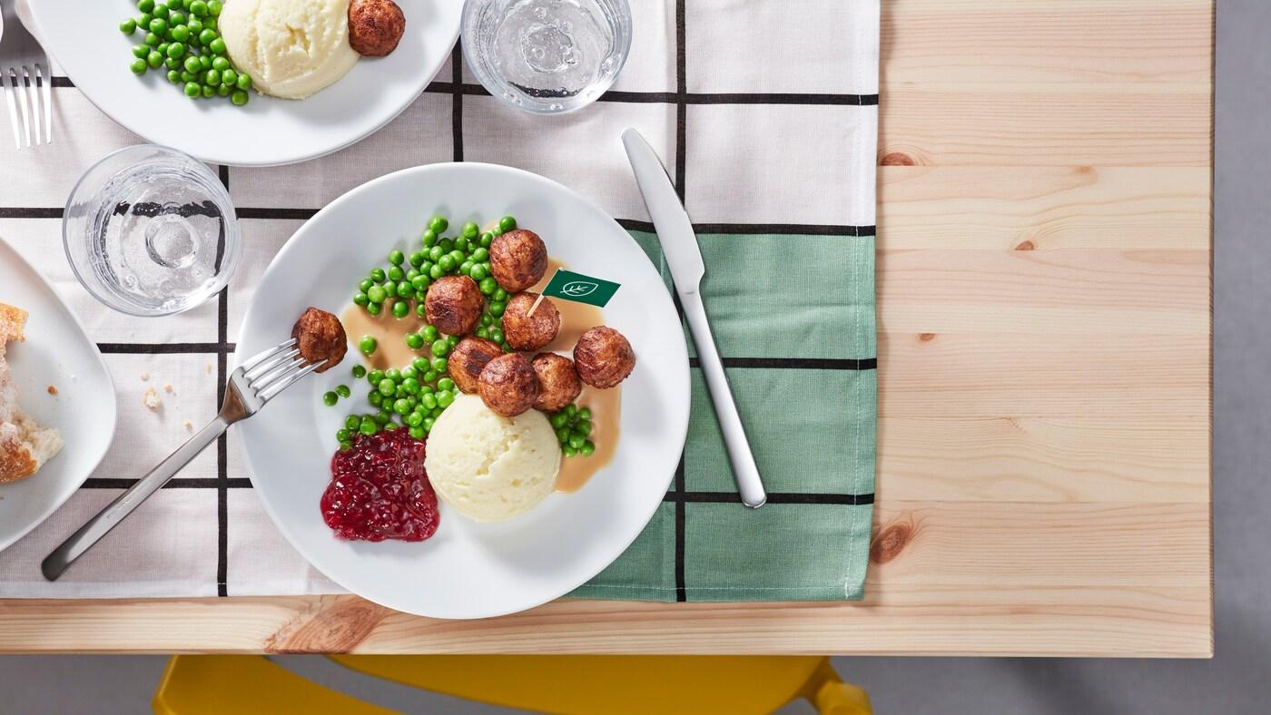 Comida sueca en un plato blanco sobre un individual en una mesa de madera.