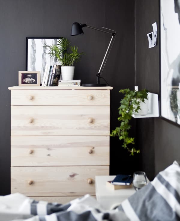 Commode en bois clair dans une chambre à coucher gris foncé.
